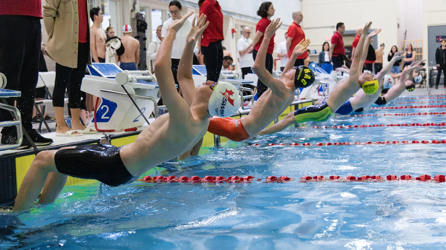 Backstroke swimmers launching backward off the wall at the start of a race